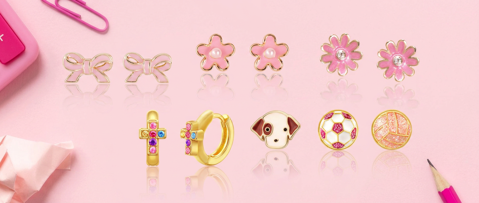 Girl Nation back to school earrings flat lay with bow, flower, dog and soccer ball studs on pink background with pencil and paperclips