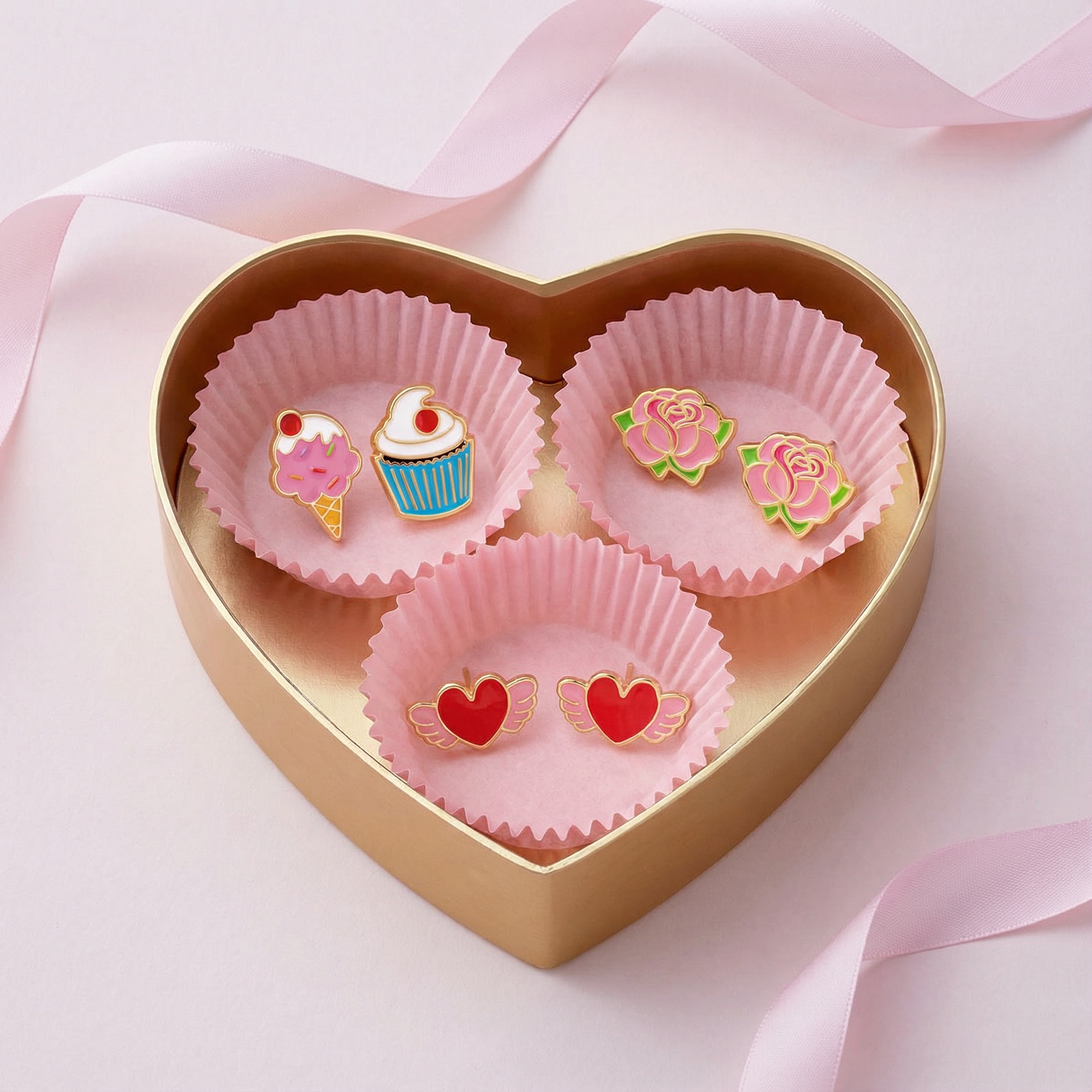 Heart-shaped gift box with dessert, rose, and winged heart stud earrings on pink ribbon background