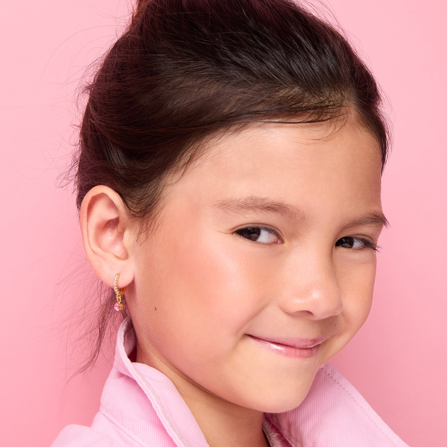 Young girl wearing 18K gold plated pink solitaire drop huggie earrings, front view