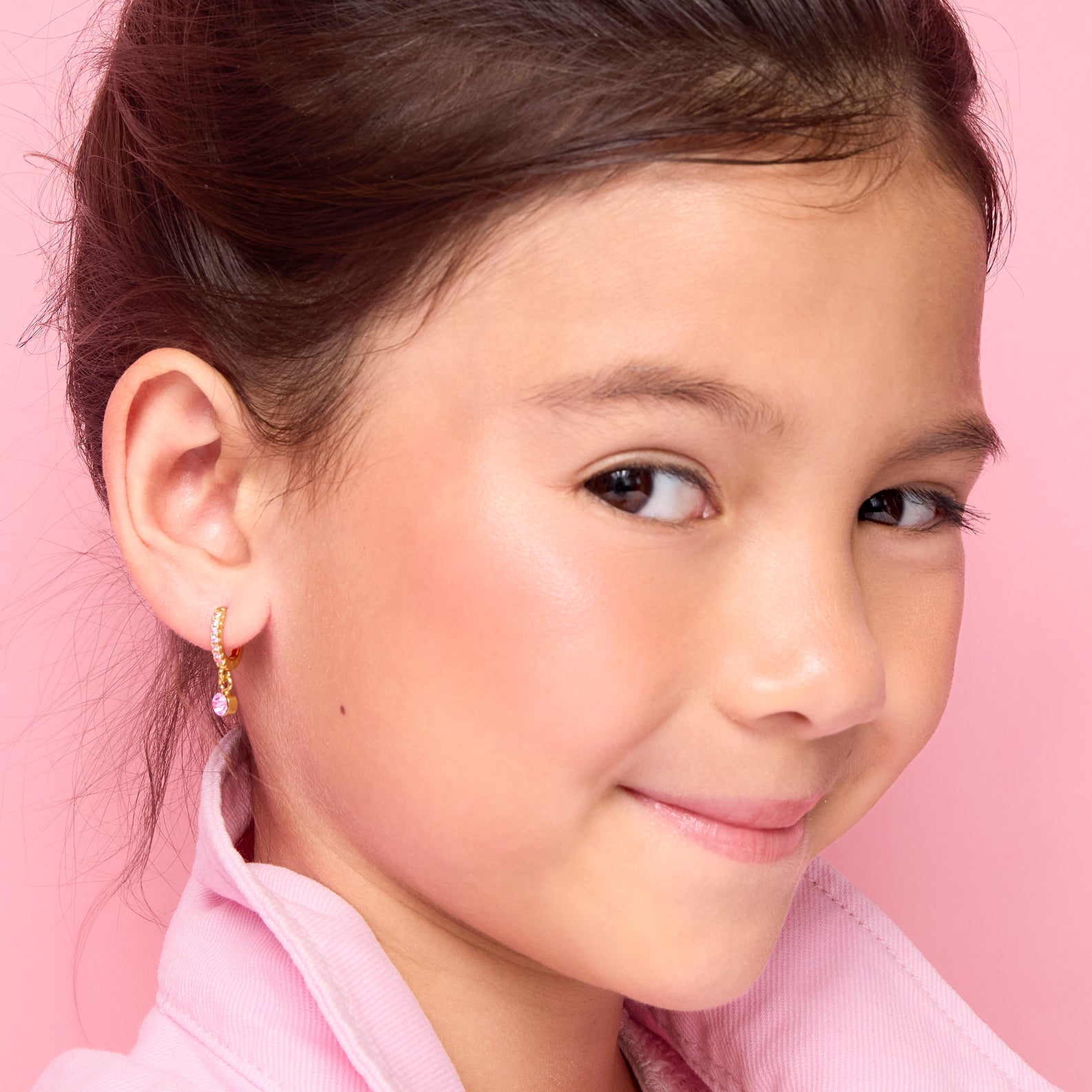  Side profile of a young girl wearing pink CZ solitaire huggie earrings by Girl Nation Canada