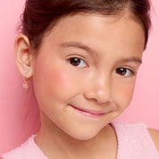 Side profile of a young girl wearing pink CZ flower charm huggie earrings by Girl Nation Canada
