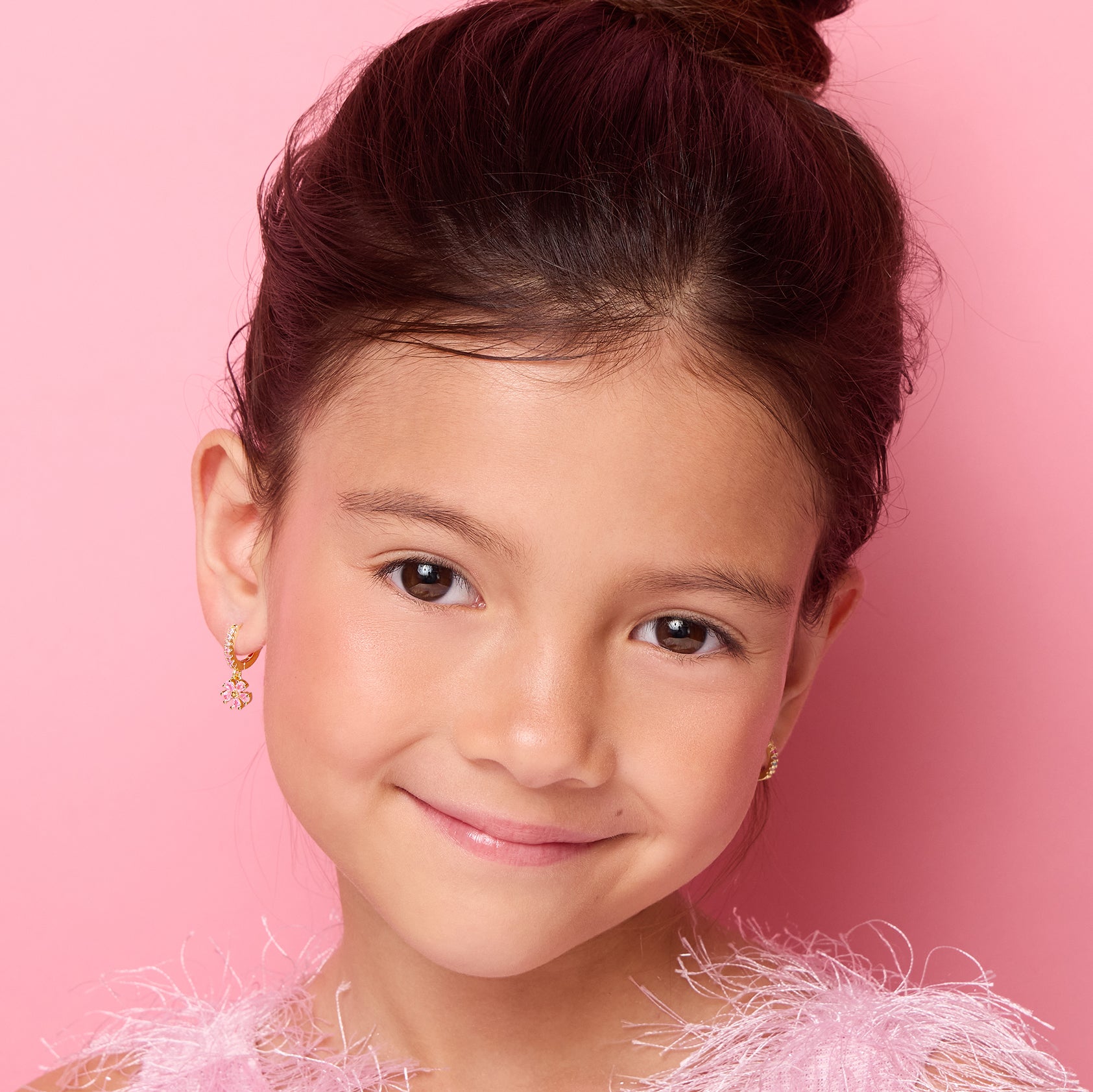 Young girl wearing 18K gold plated pink flower huggie earrings, close-up front view