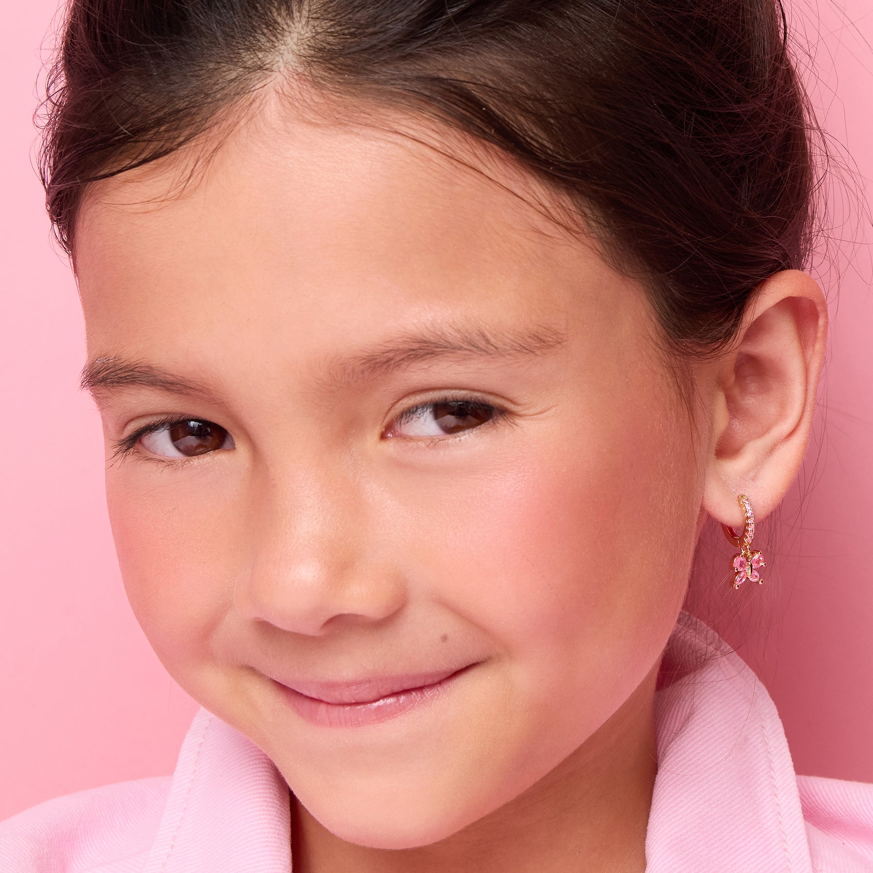 Young girl wearing 18K gold plated pink butterfly huggie earrings by Girl Nation Canada