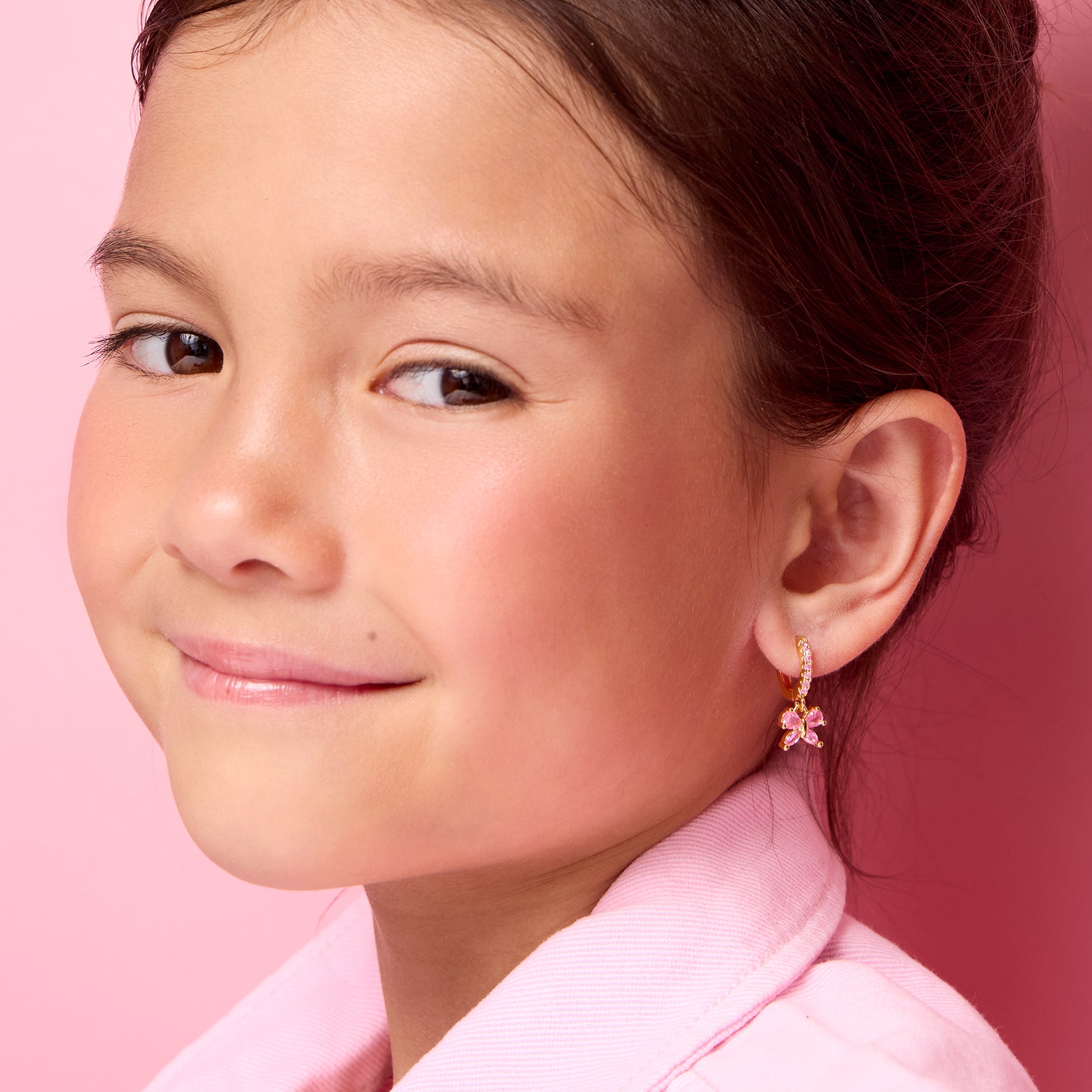 Young girl wearing 18K gold plated pink butterfly huggie earrings by Girl Nation Canada