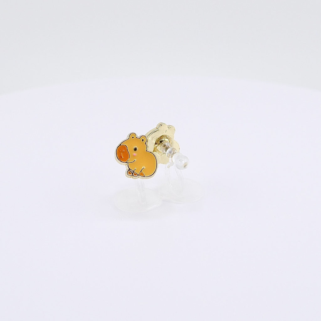 Golden-brown capybara charm clip-on earrings rotating on display, video