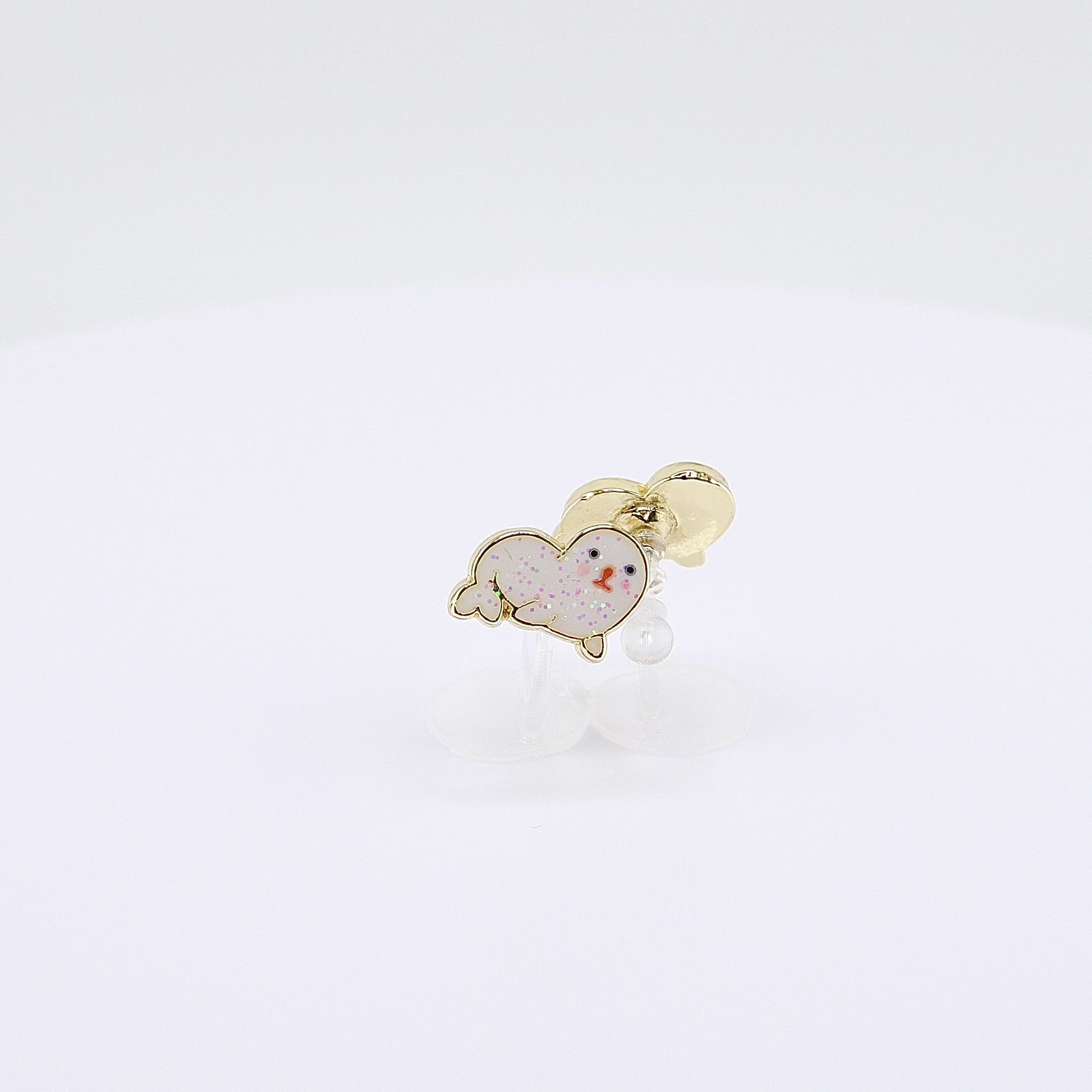 Glittery white seal charm clip-on earrings rotating on display, video